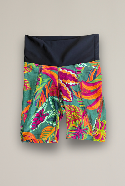 Colorful tropical patterned Mauri shorts with a black waistband on a beige background