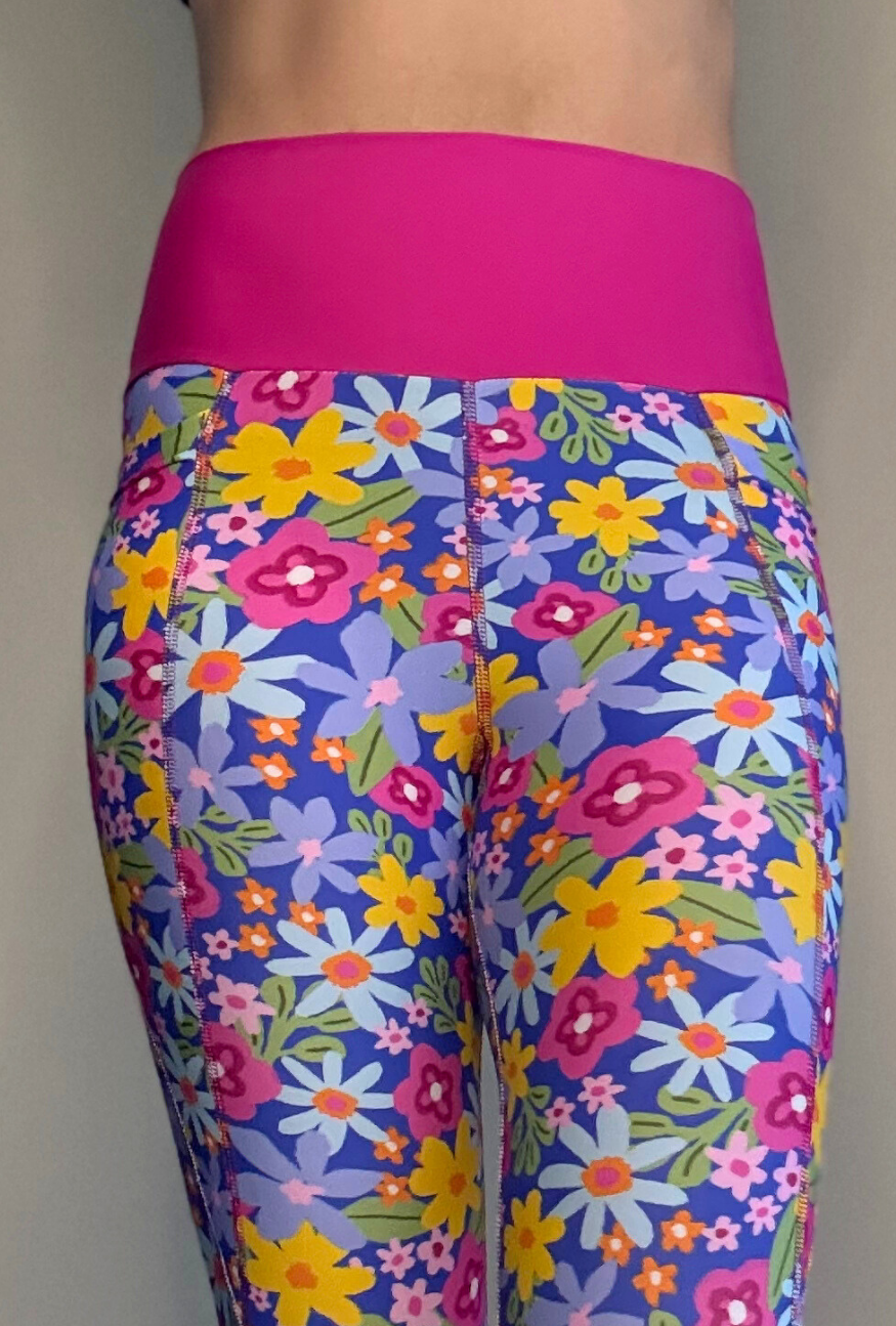 Colorful floral-patterned leggings with a bright pink waistband on a plain background