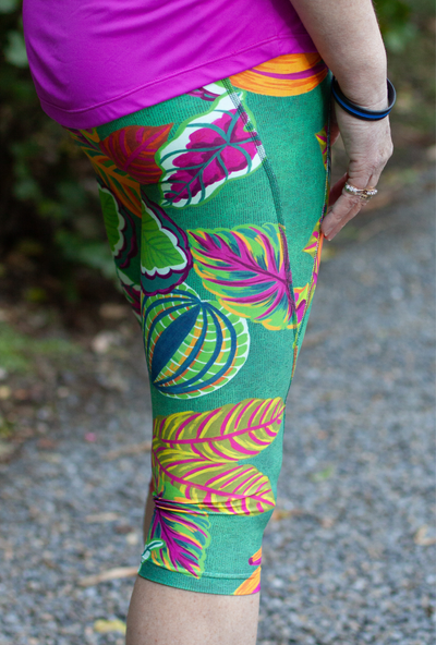 Colorful tropical leaf-patterned Raumati capri leggings worn by a person outdoors.