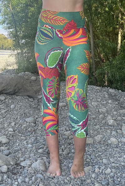Person wearing colourful capri leggings with a leaf pattern standing on a rocky ground.