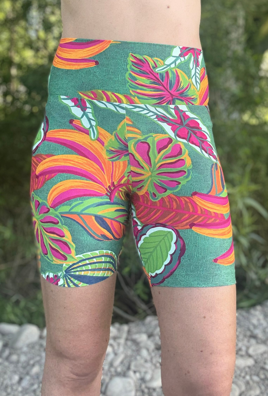 Person wearing colourful tropical leaf patterned shorts with a natural background
