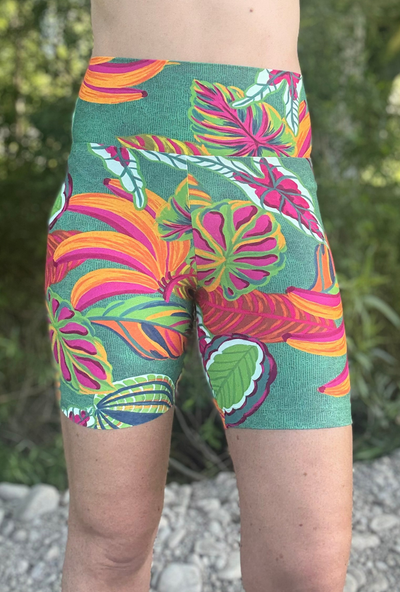 Person wearing colourful tropical leaf patterned shorts with a natural background