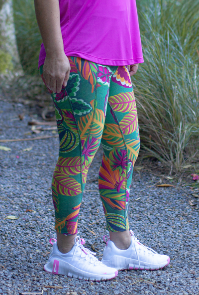 Person wearing colourful leaf-patterned leggings and a pink top outdoors.