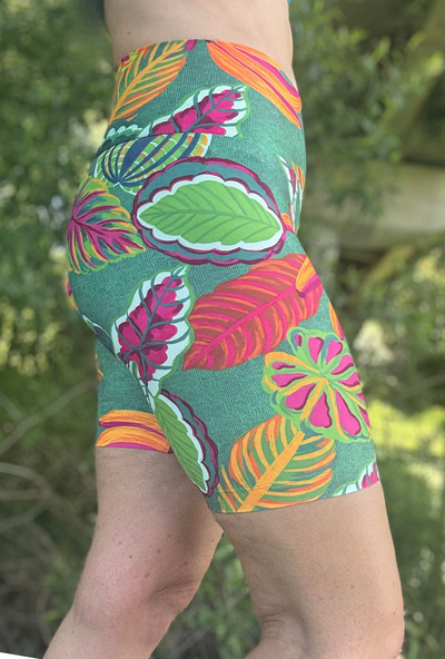 Colourful tropical leaf patterned shorts worn by a person with a blurred natural background