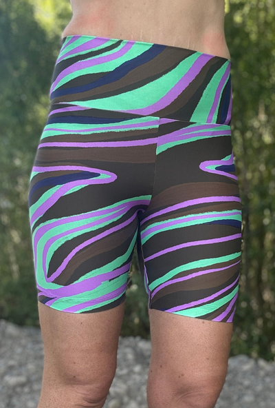 Person wearing colourful striped shorts with a blurred natural background