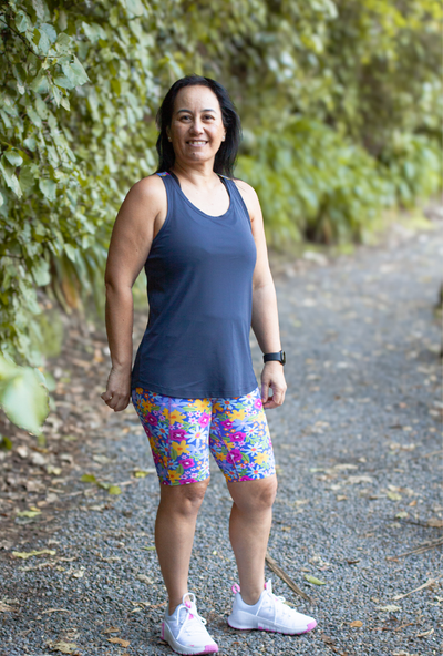 Woman in athletic wear standing on a path with greenery in the background